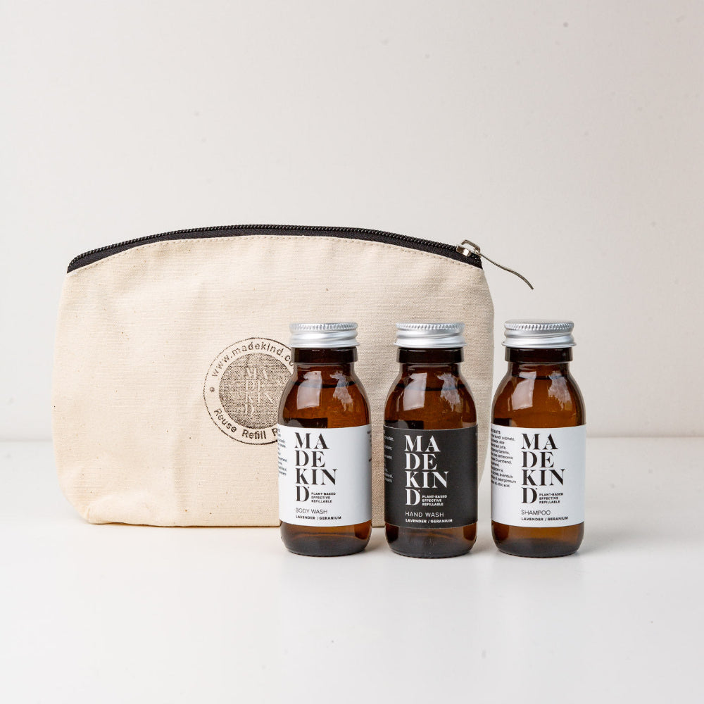 Three bottles of Madekind products Body wash, hand wash and shampoo with a beige reusable pouch on a white background