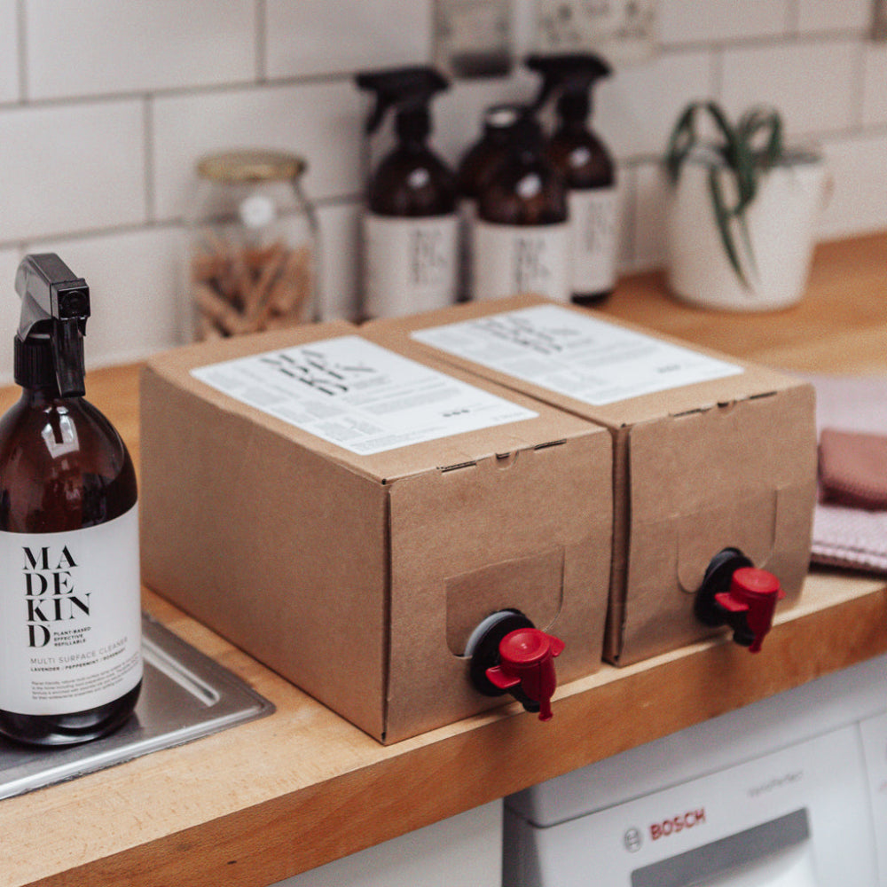 Two cardboard boxes Natural dog shampoo with labels on a kitchen counter next to a bottle labelled 'MADE KIND'.