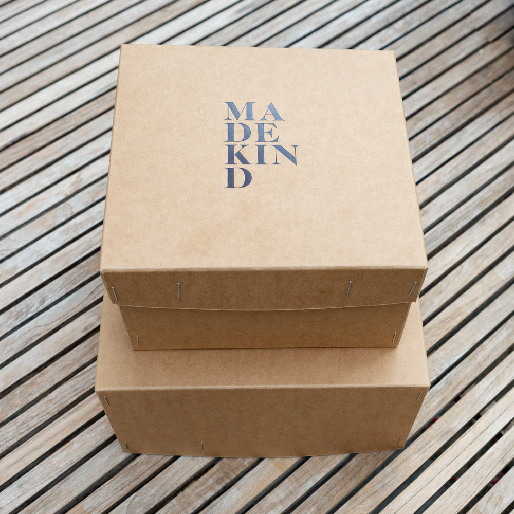 Two brown cardboard boxes with 'MADE KIND' text on a wooden surface