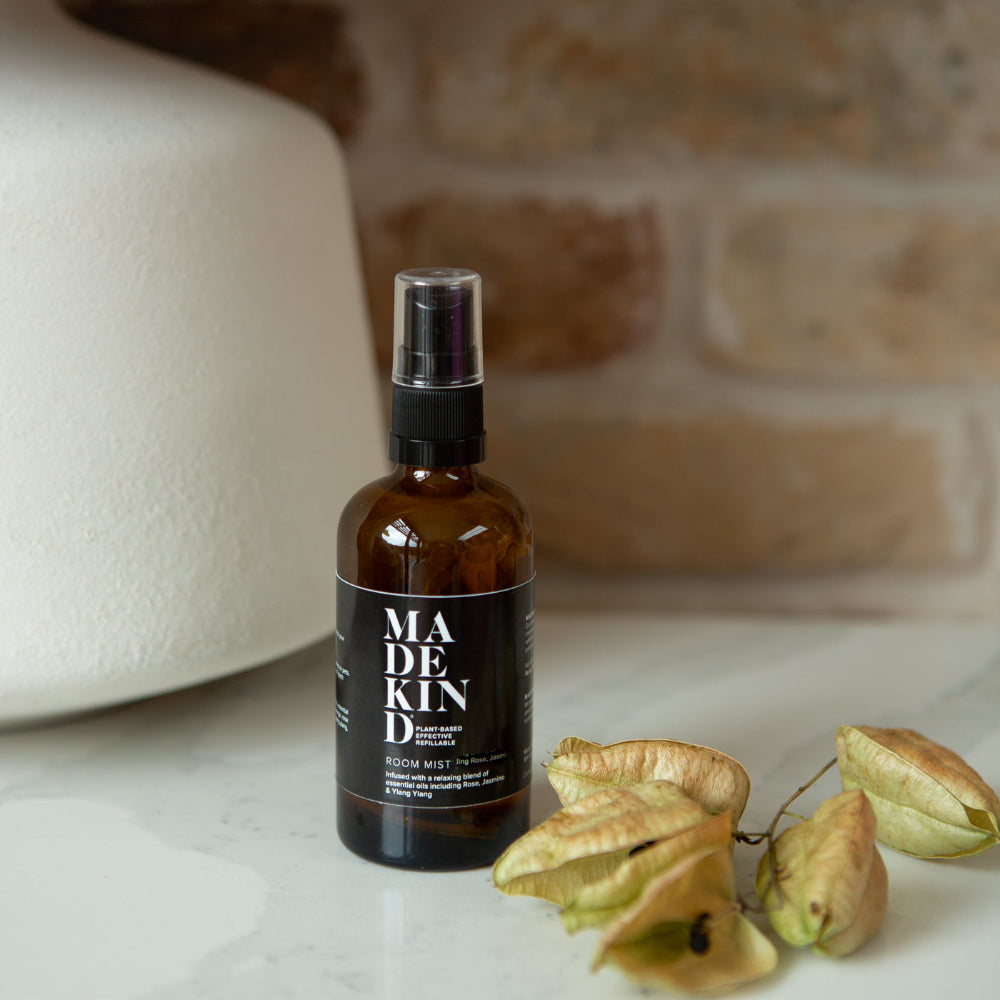 Brown spray bottle labelled 'MADEKIND' on a marble surface with decorative elements.