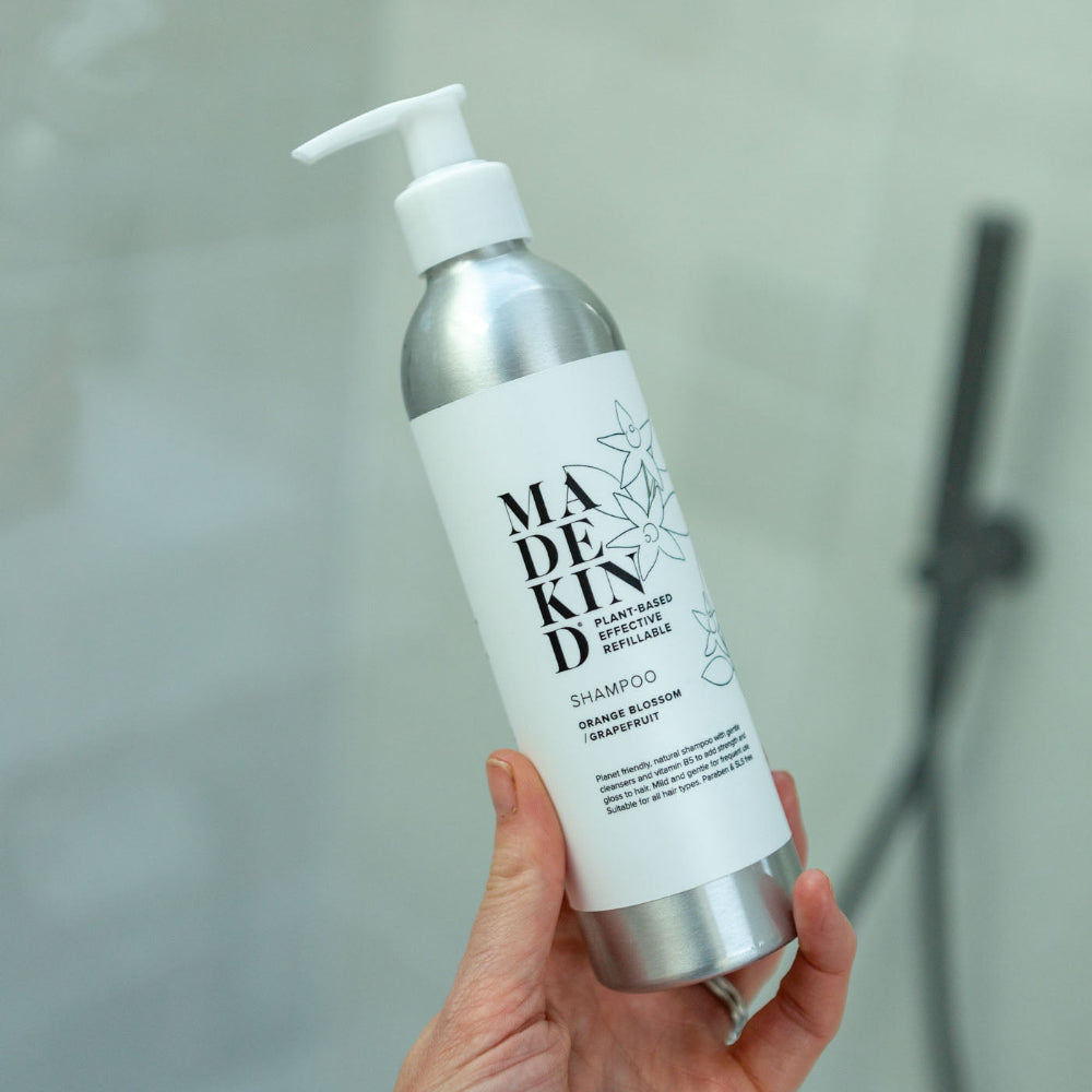 Madekind shampoo bottle held in a hand with a neutral background