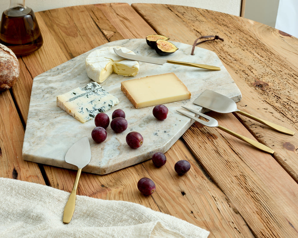 Cheeseboard with assorted cheeses, figs, and grapes on a wooden table.
