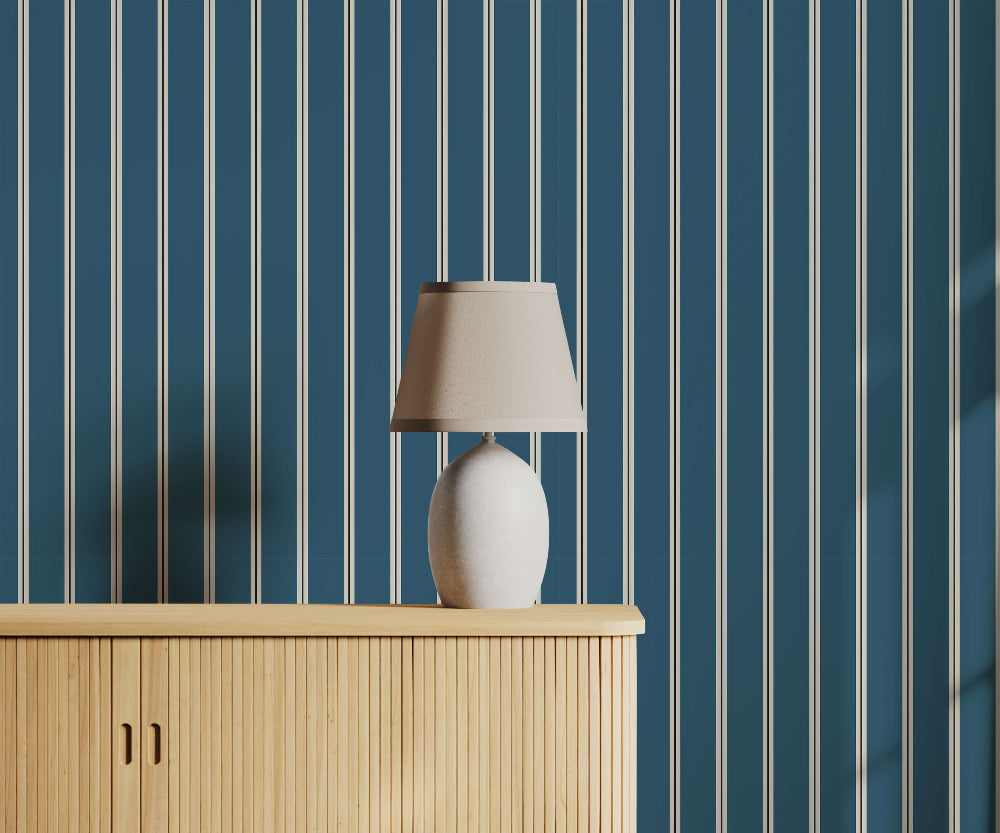 Lamp on a wooden cabinet against blue striped wallpaper