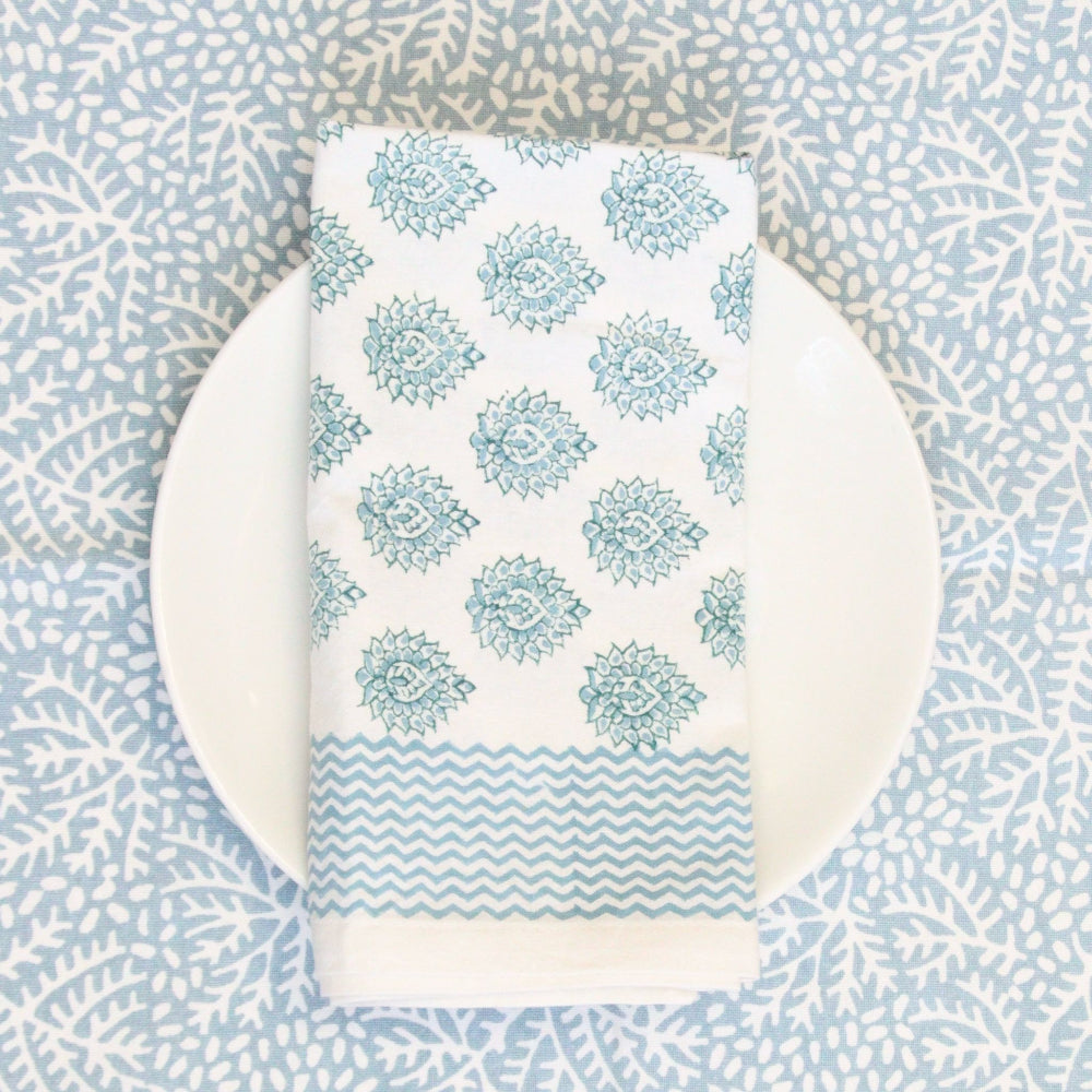 Teal patterned napkin on a white plate with a blue and white geometric background