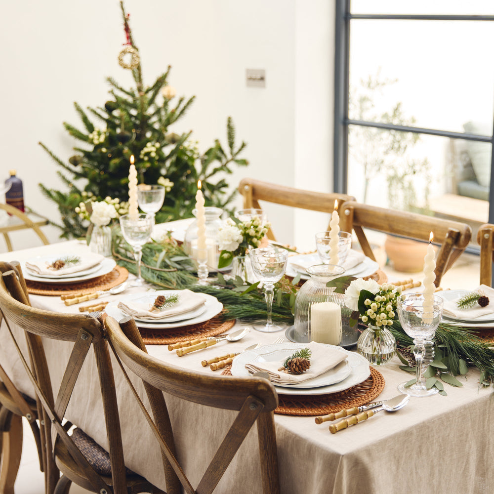 Dining table set for a festive meal with Christmas decorations.