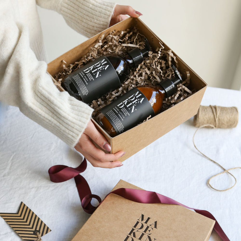 Two bottles of 'MADEKIND' in a gift box with ribbons on a light surface.