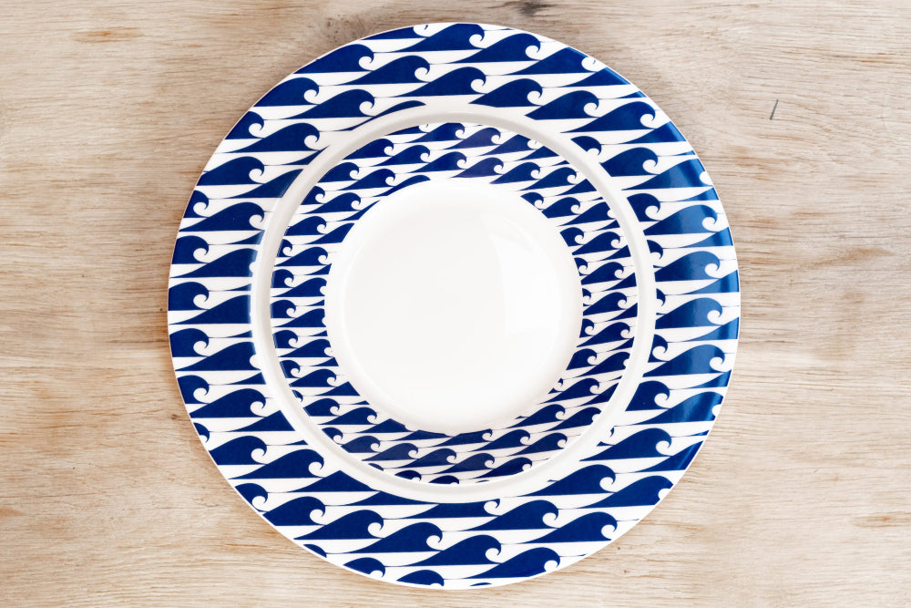 Two round ceramic plates with blue wave patterns on a wooden surface