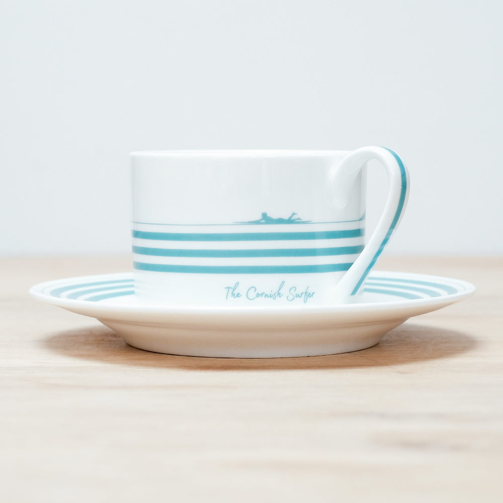 Ceramic cup and saucer with blue stripes on a light background