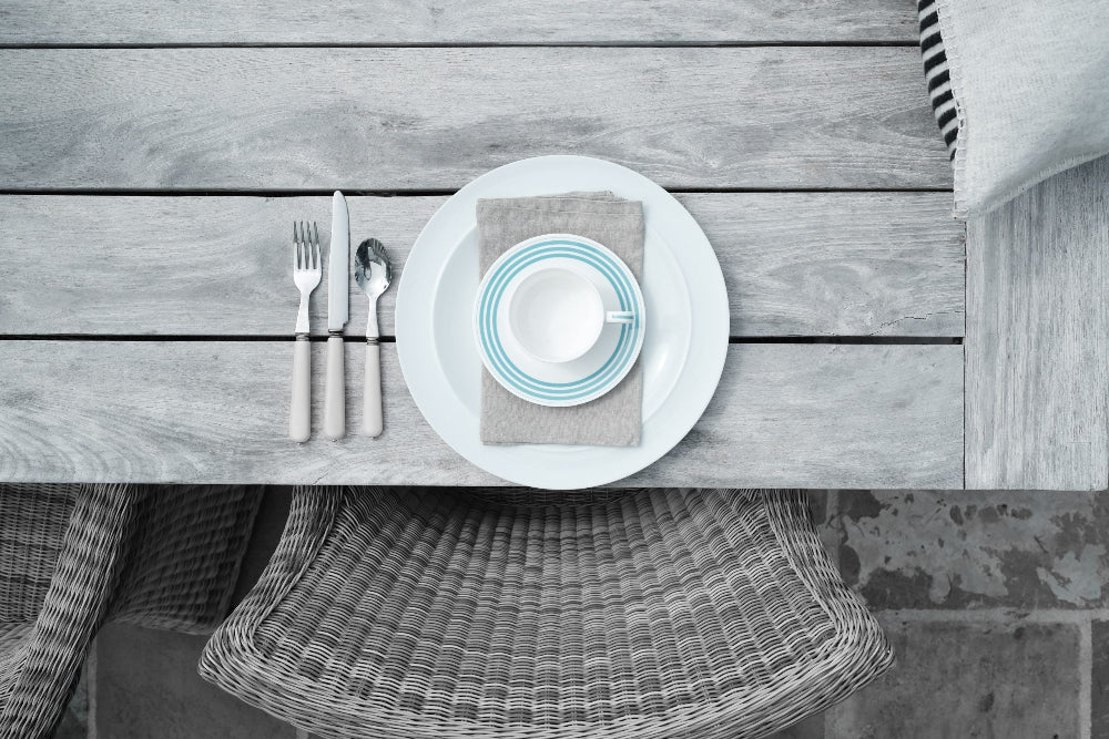 Dining table setting with plates, cutlery, and a bowl on a wooden surface.
