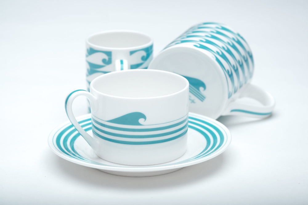 Ceramic tea set with turquoise wave design on a white background