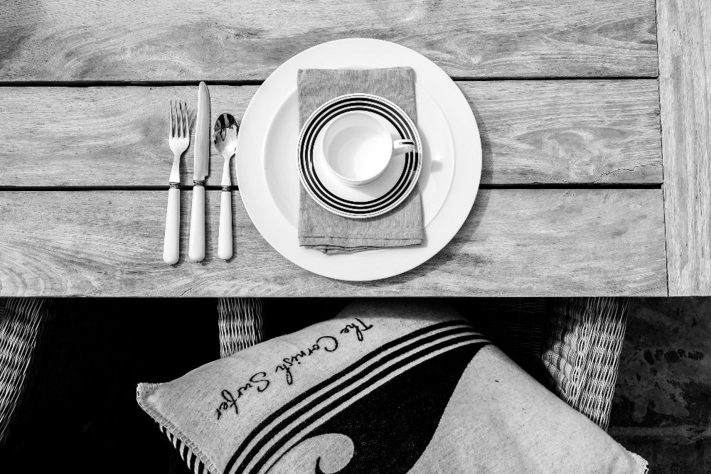 Table setting with plates, napkins, and cutlery on a wooden table.