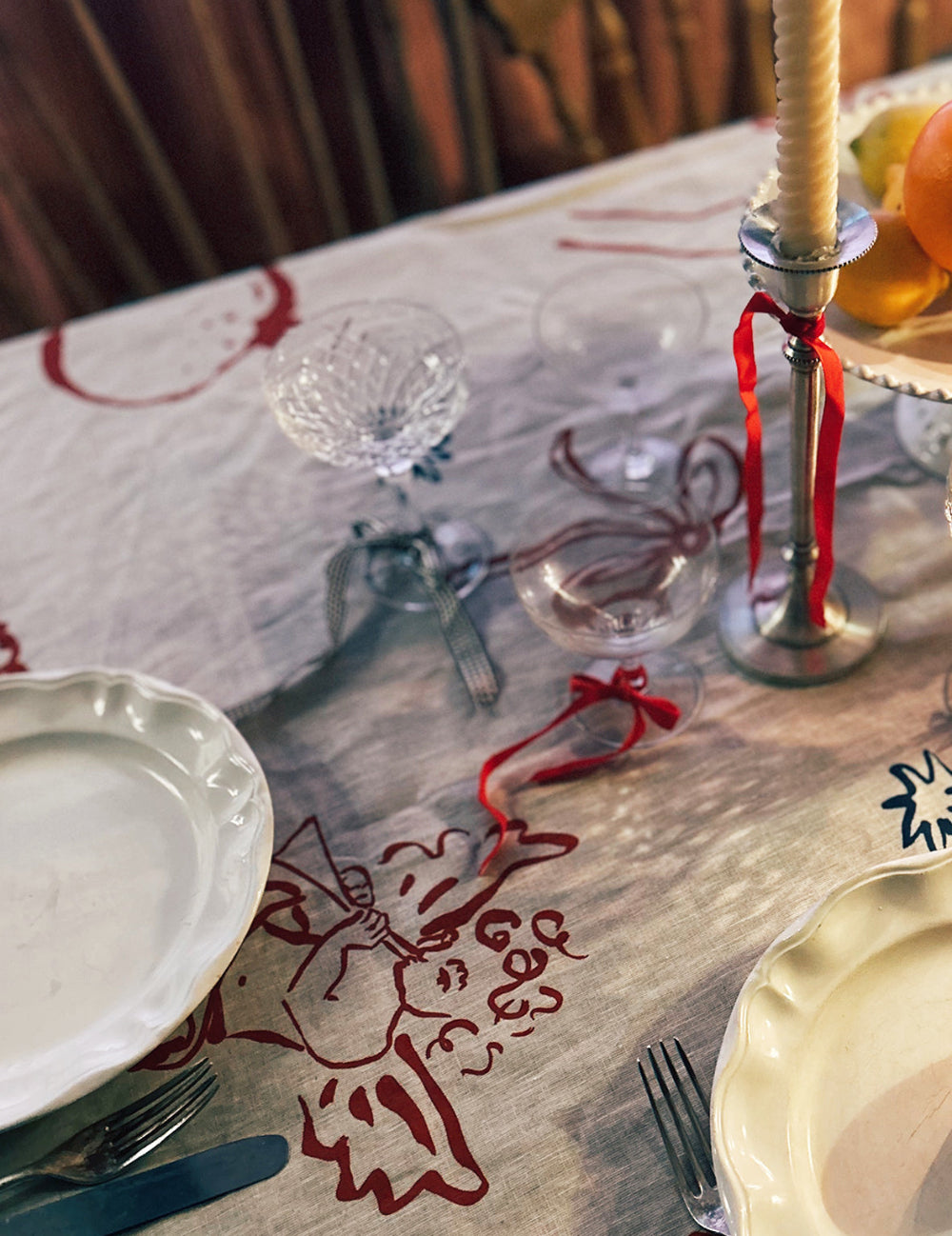 Christmas dining table setting with plates, glasses, and a decorative tablecloth.