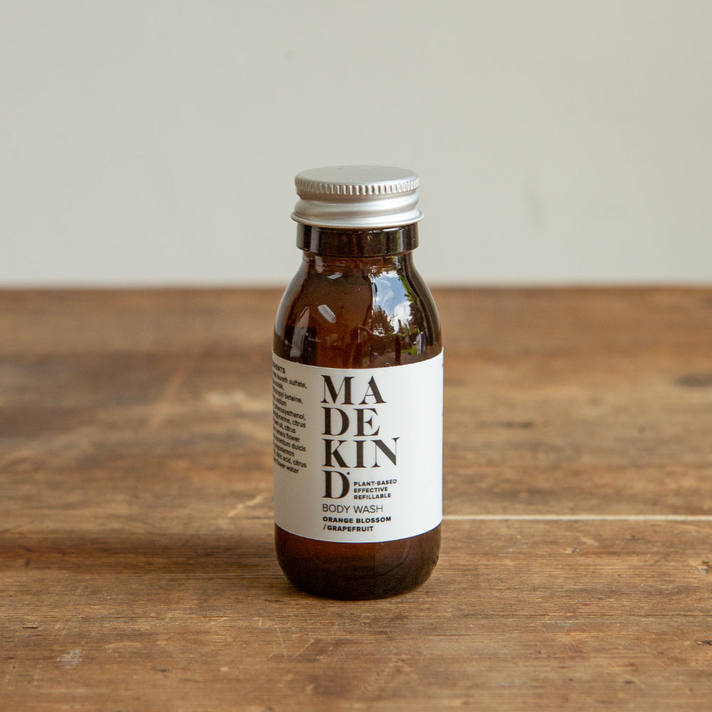 Bottle of Made Kind body wash on a wooden surface with a neutral background