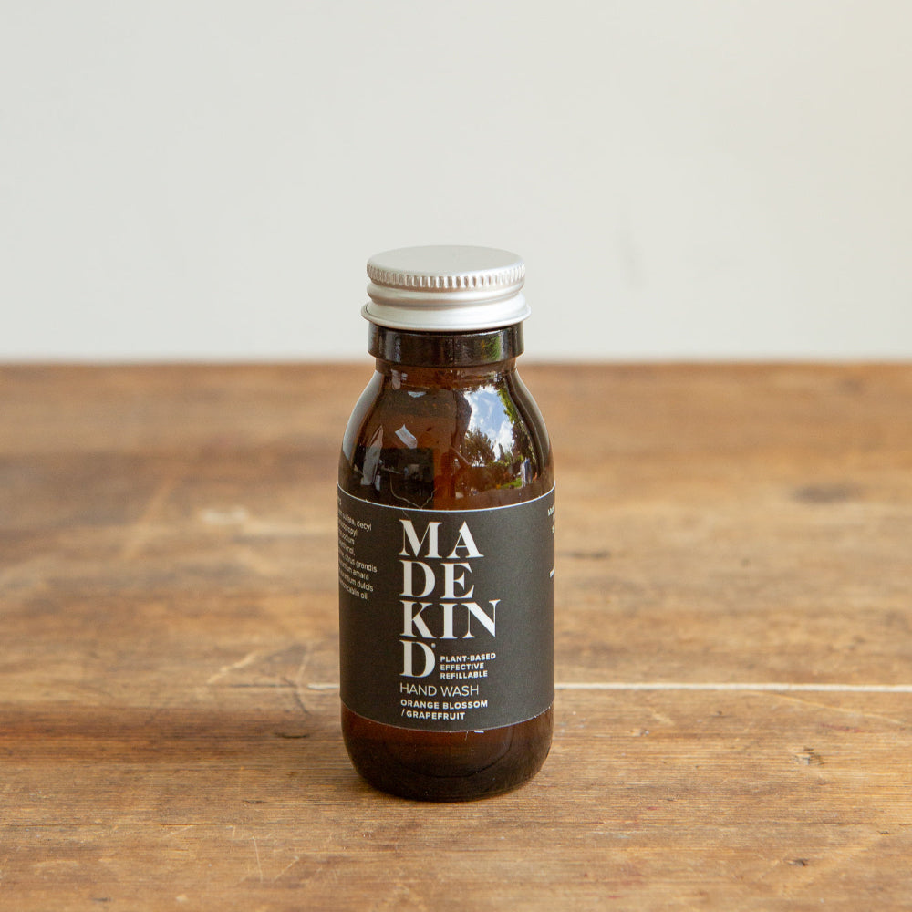 Bottle of Madekind hand wash on a wooden surface with a neutral background