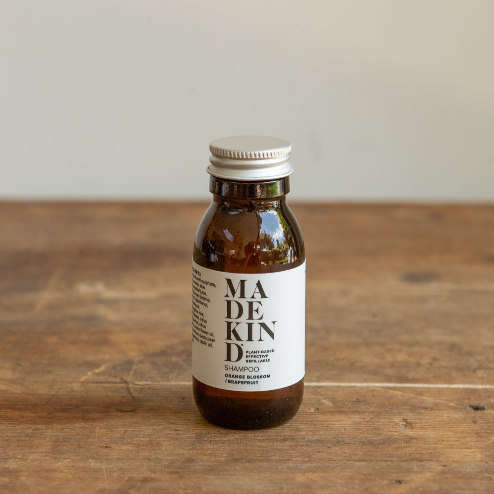 Bottle of Madekind mini shampoo on a wooden surface with a neutral background