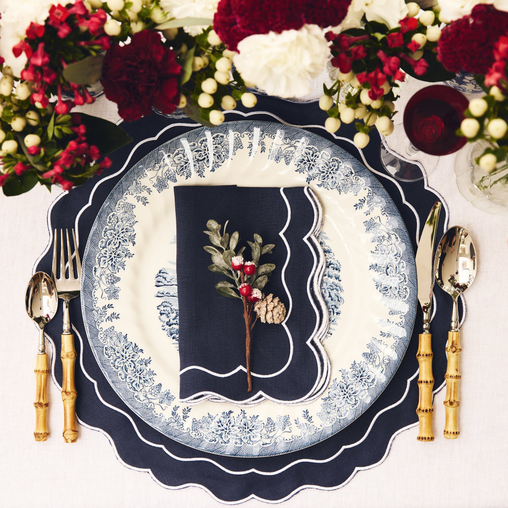 Decorative table setting with floral arrangement, plates, and cutlery on a white background