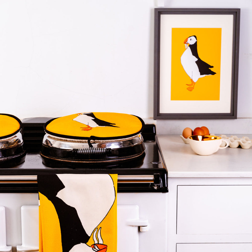 Kitchen with puffin-themed towels and decor on a stove and wall.