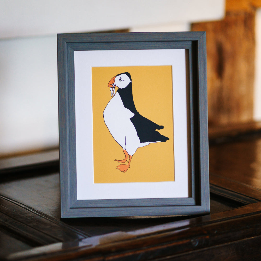 Framed artwork of a puffin on a yellow background