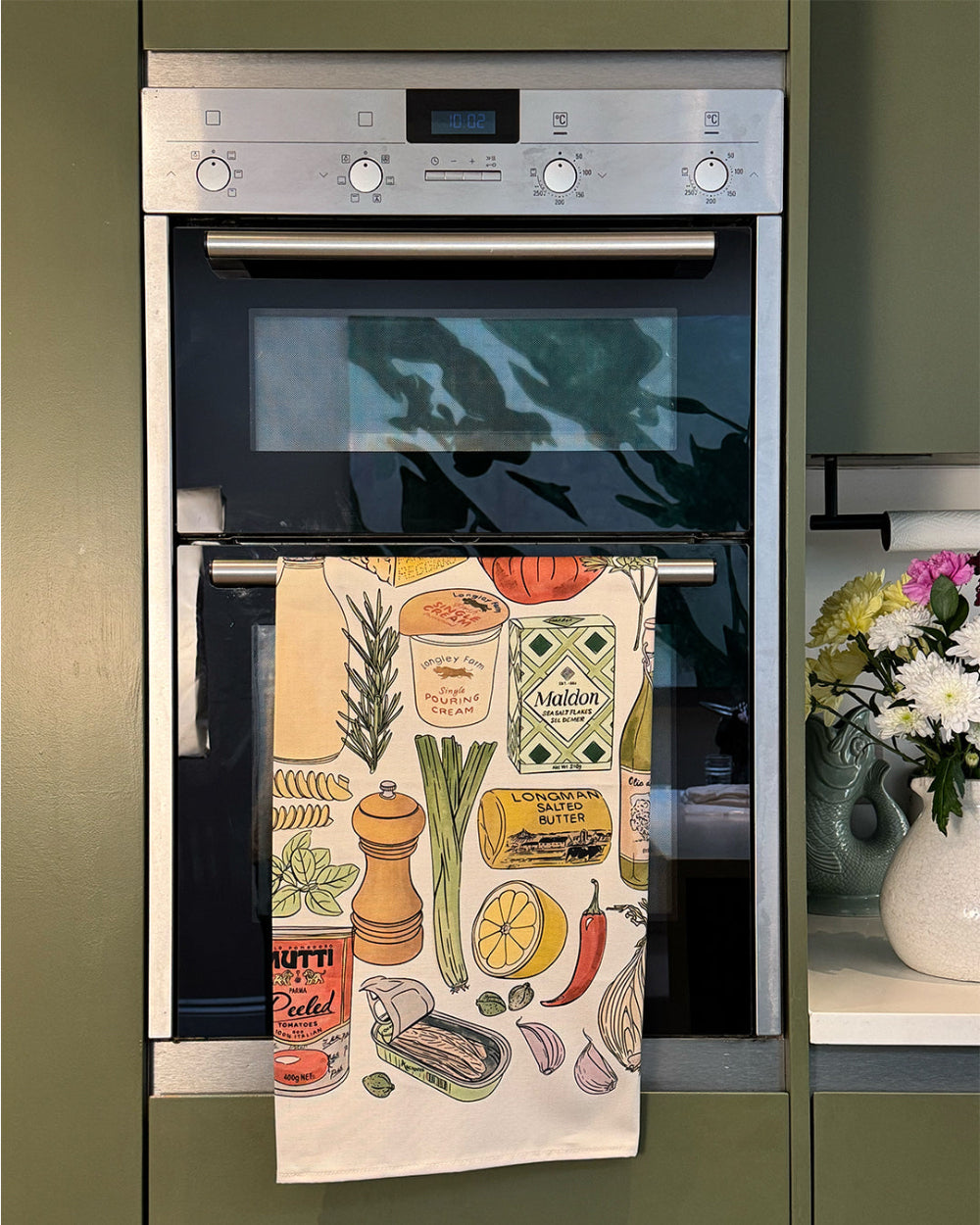 Decorative kitchen towel with food illustrations hanging on a kitchen appliance.