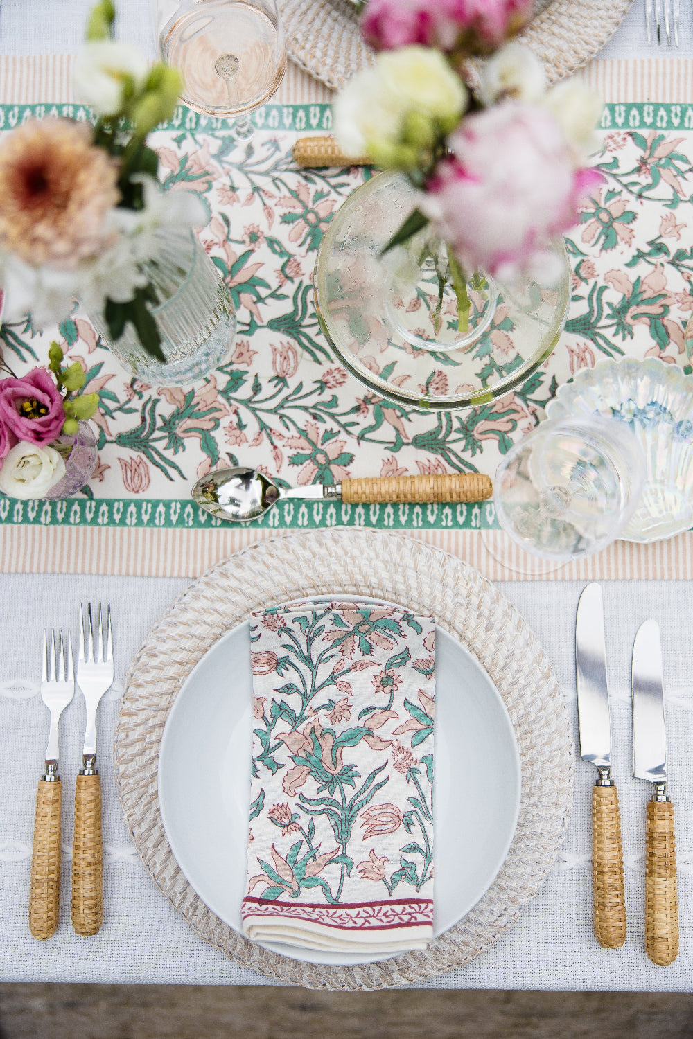 Elegant table setting with floral patterns on plates and placemats.
