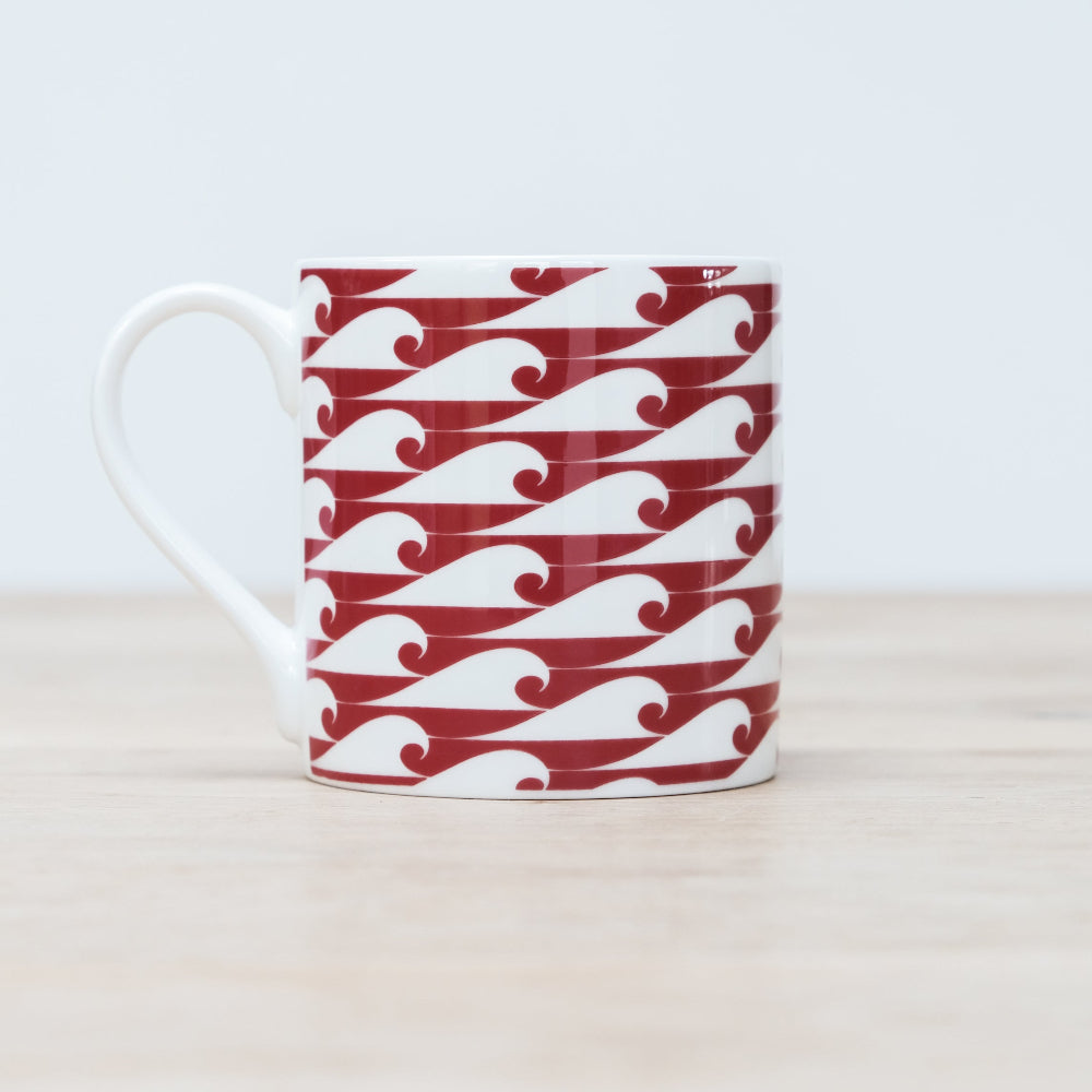 Mug with red and white wave pattern on a light background