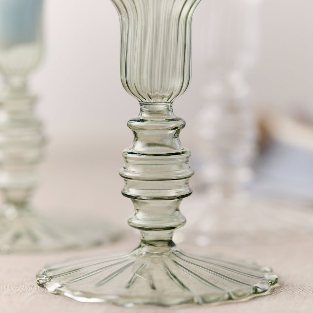 Close-up of a sage green glass candle holder with ribbed design on a neutral background