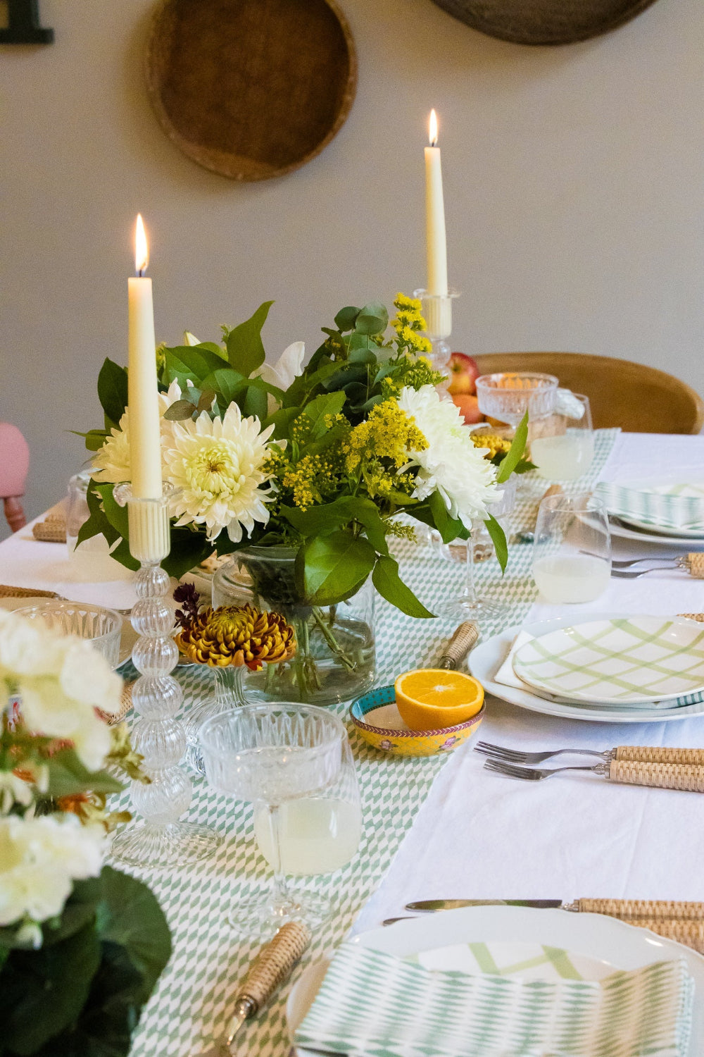 Elegant table setting with candles, flowers, and cutlery on a white tablecloth.