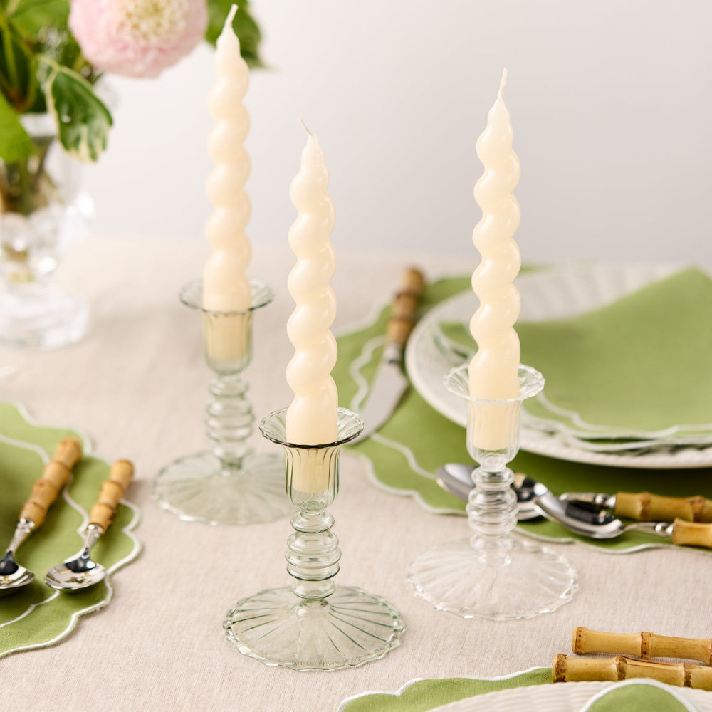 Decorative table setting with spiral candles, green plates, and bamboo cutlery.