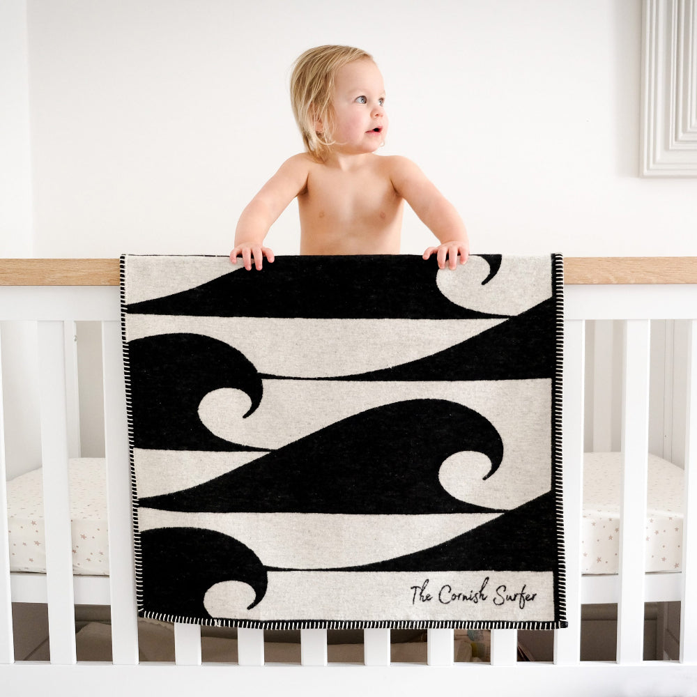 Child standing on a crib with a black and white patterned blanket