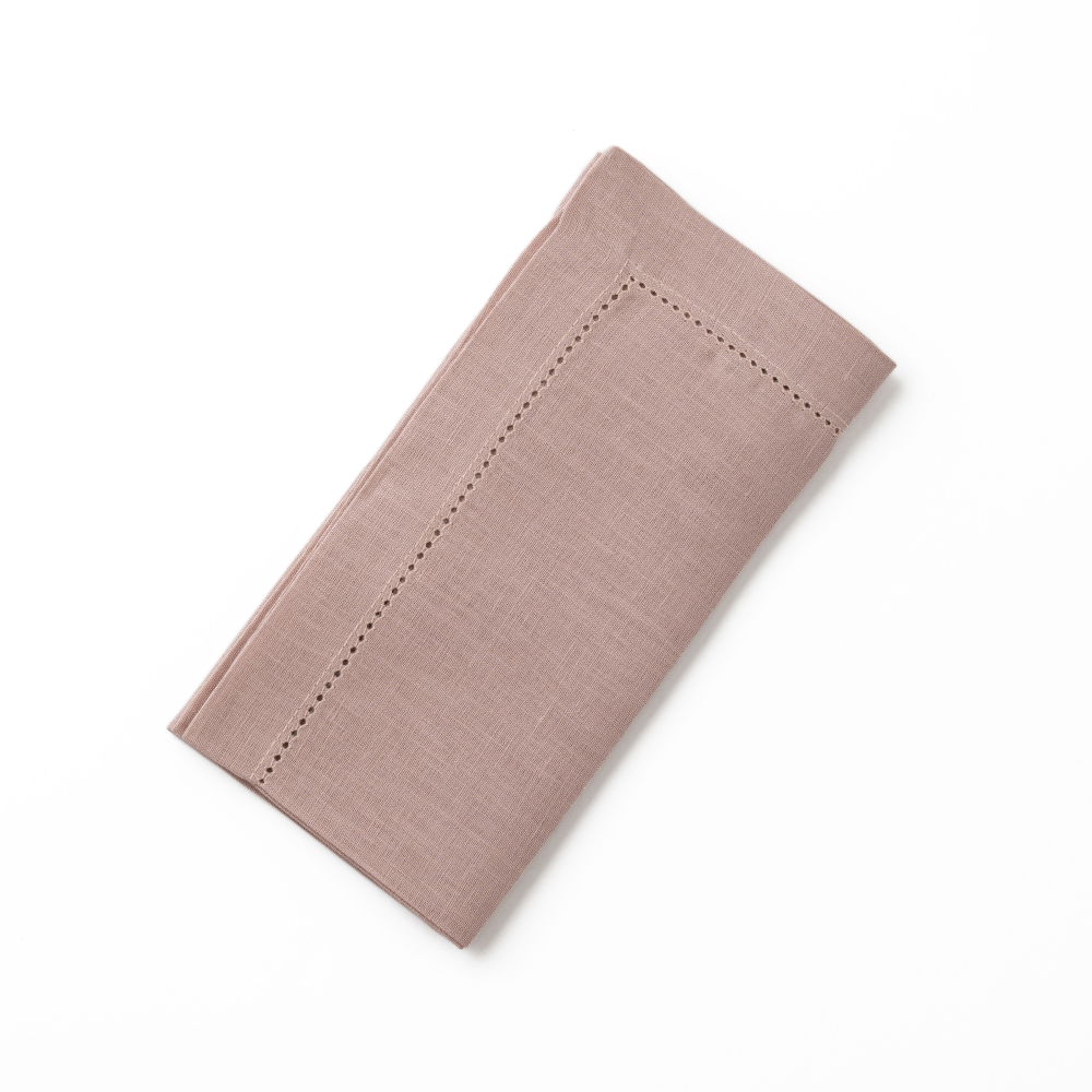 Folded pink dusty linen napkin on a white background