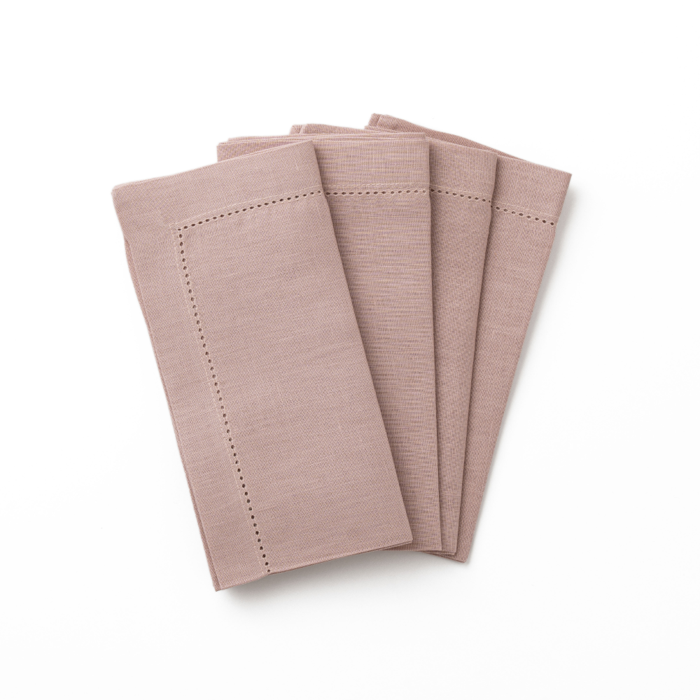 Set of four dusty pink hemstitched linen napkins on a white background