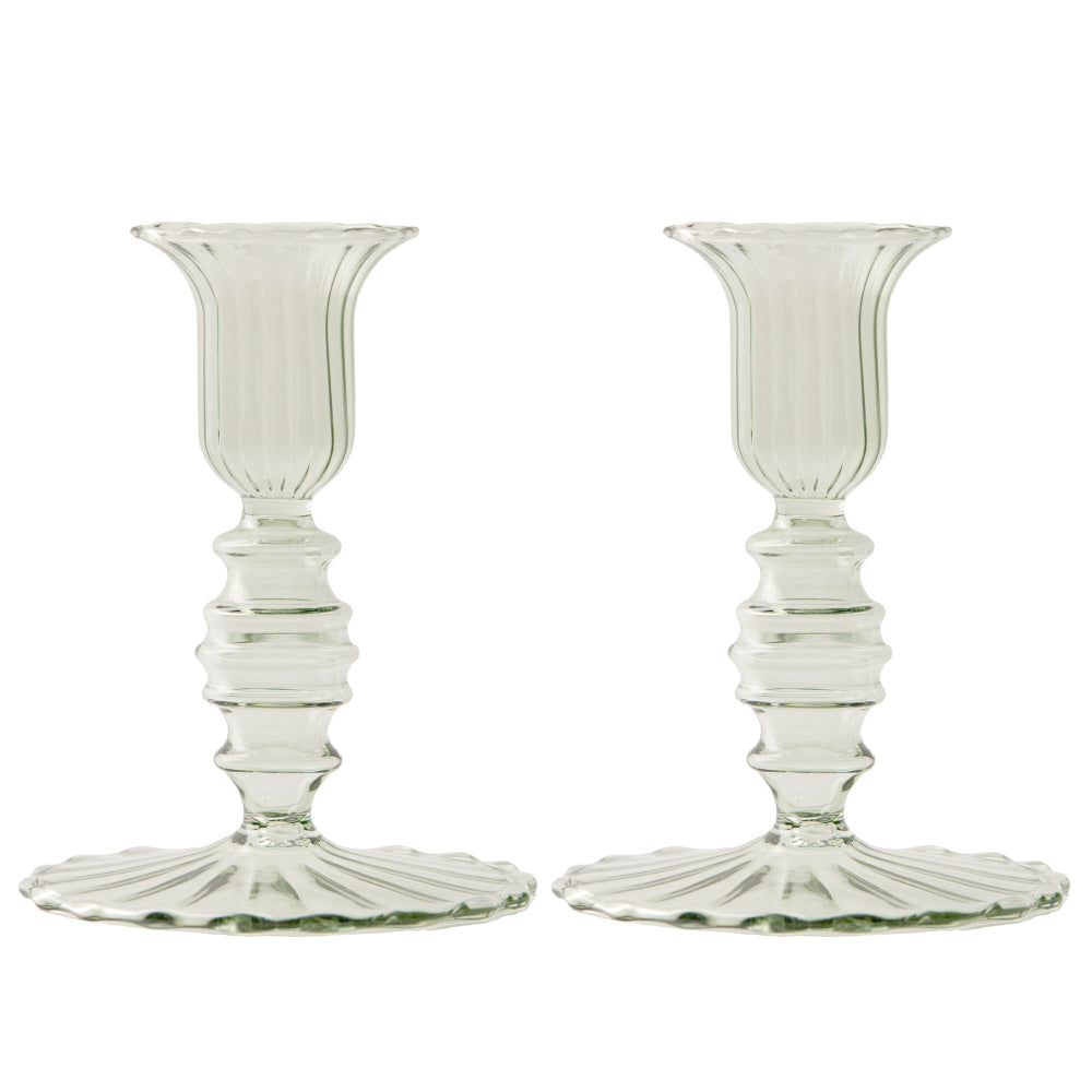 Two sage green glass candle holders on a white background