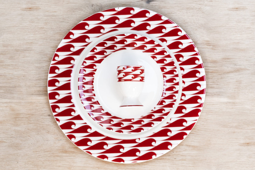Set of red and white patterned plates and egg cup on a wooden surface