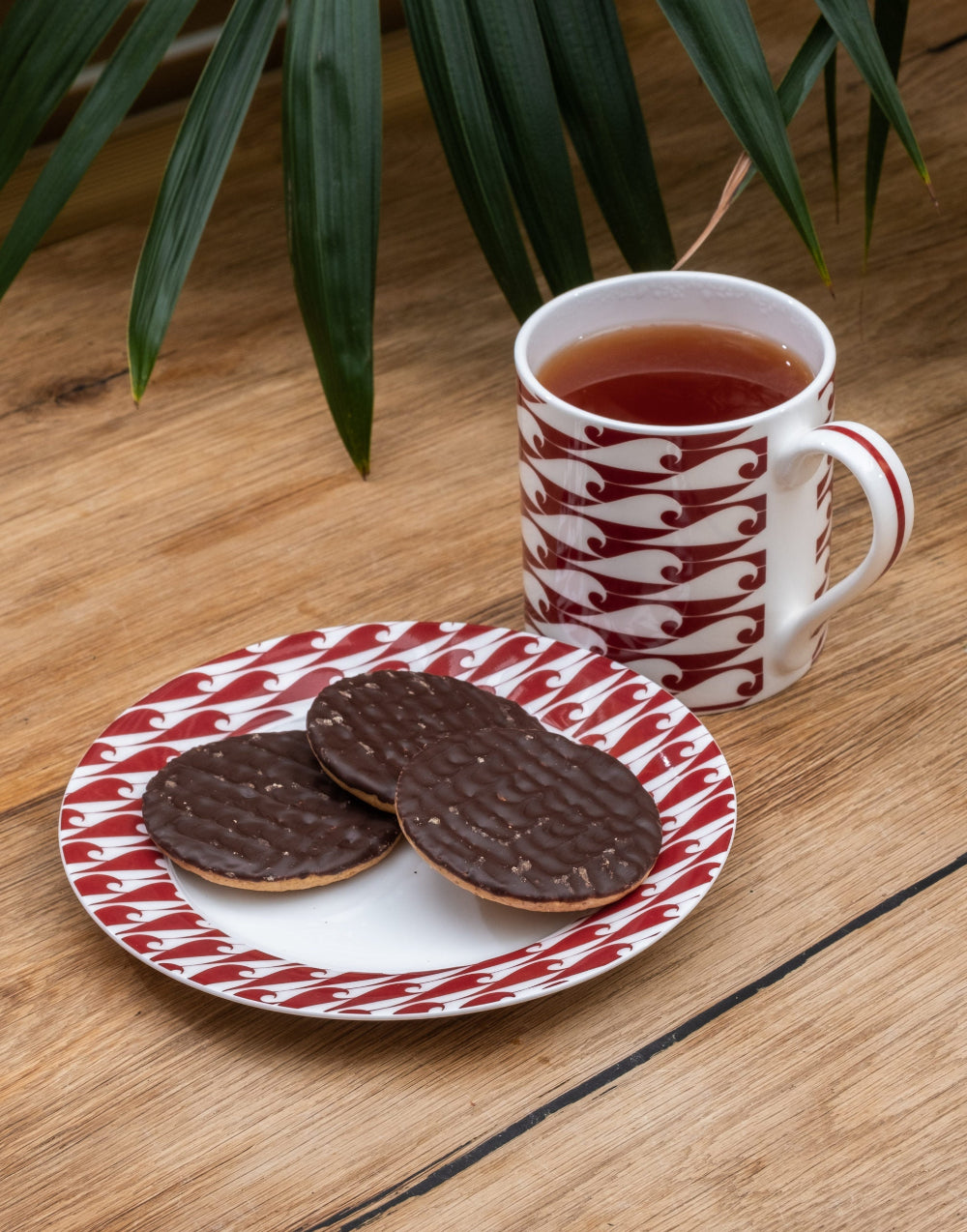 Cup of tea with a patterned saucer and cookies on a wooden table