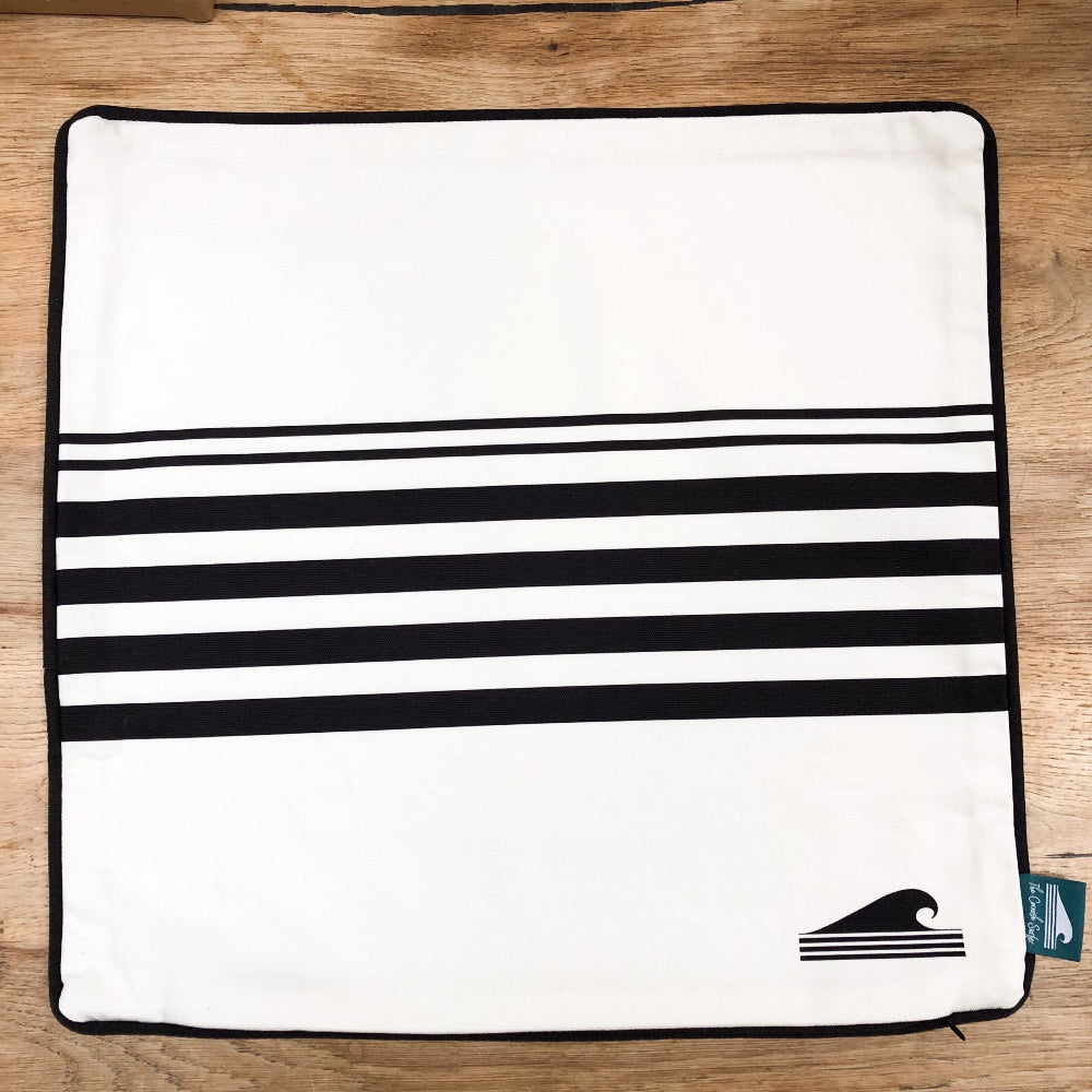 White and black cushion cover with black stripes on a wooden surface