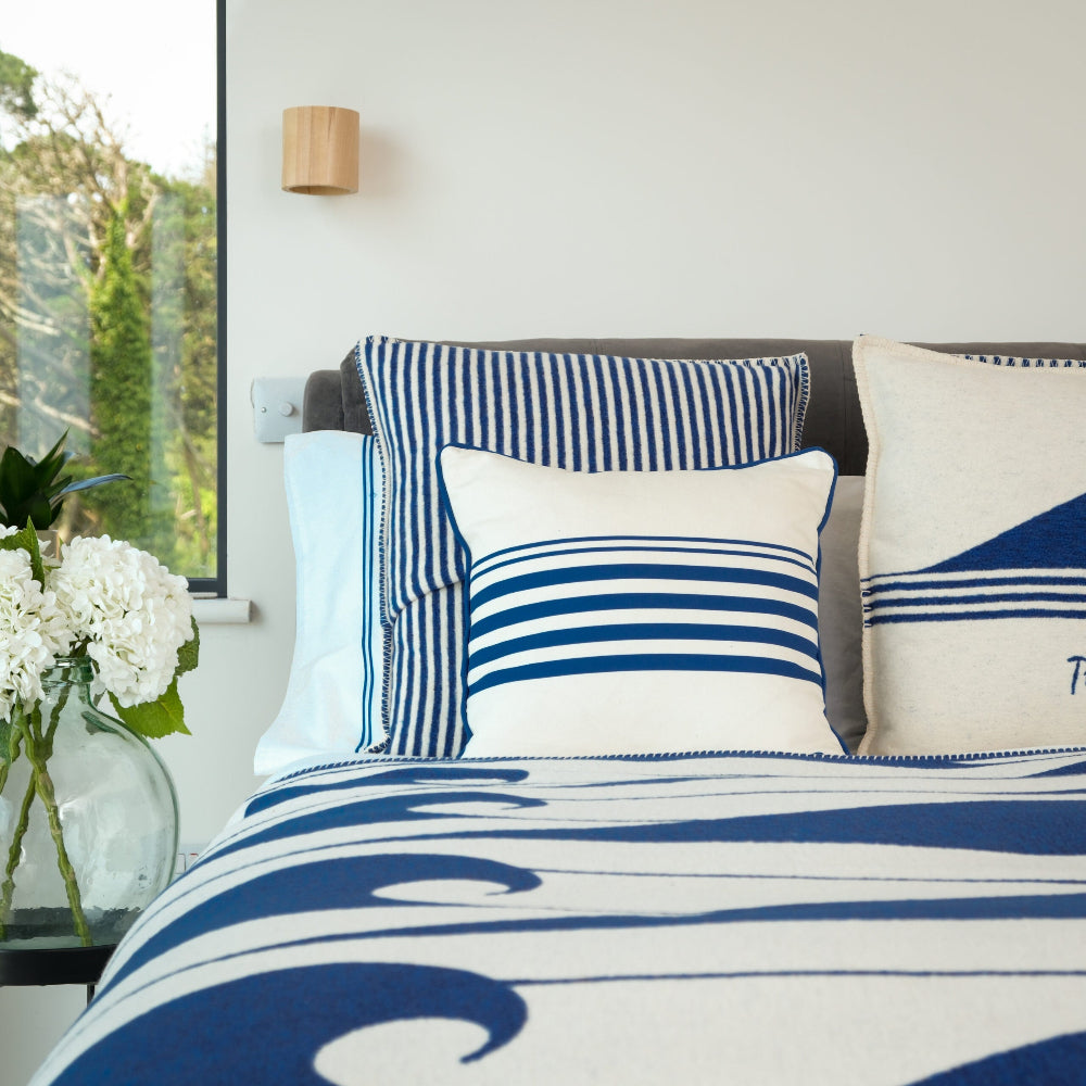Striped Blue and White Cushion with Wave Duet cover in a bedroom setting with white flowers in a vase.