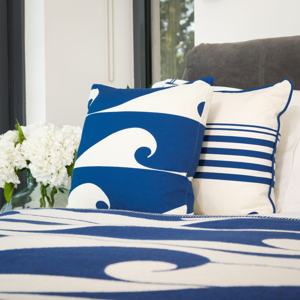 Blue and white wave-patterned pillows on a bed with matching bedding.