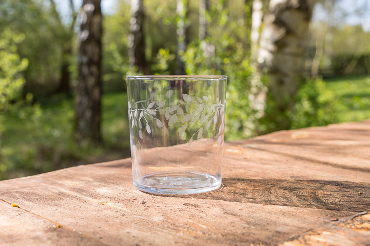 Clear glass with floral etching on a wooden surface outdoors