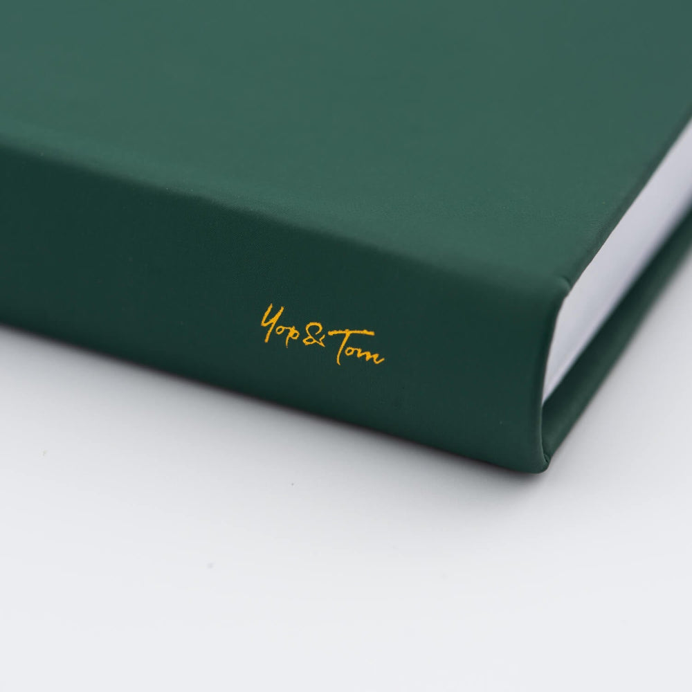 Green notebook with 'Yop & Tom' on spine of notebook on a white background