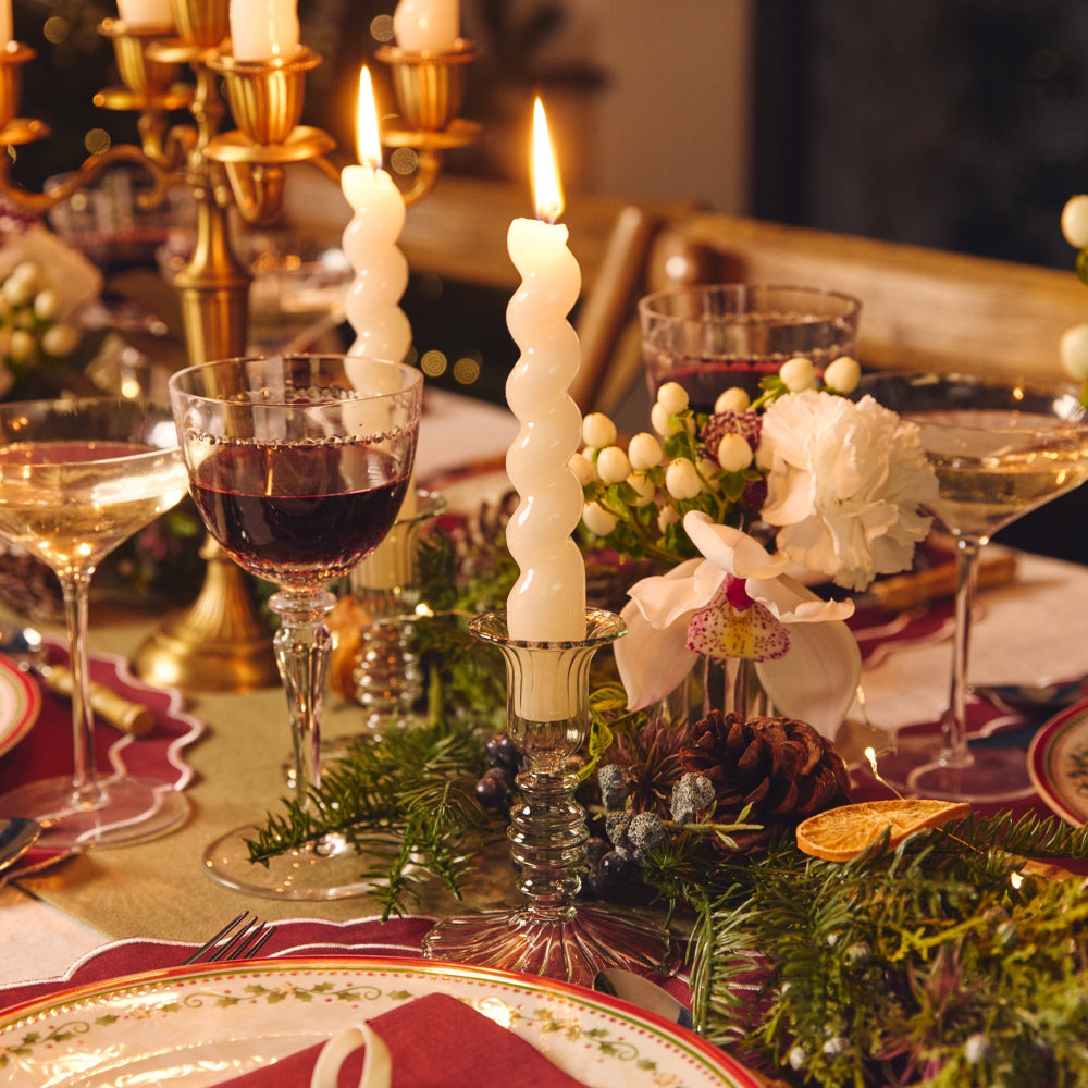 Decorative table setting with candles, glasses, and floral arrangements.