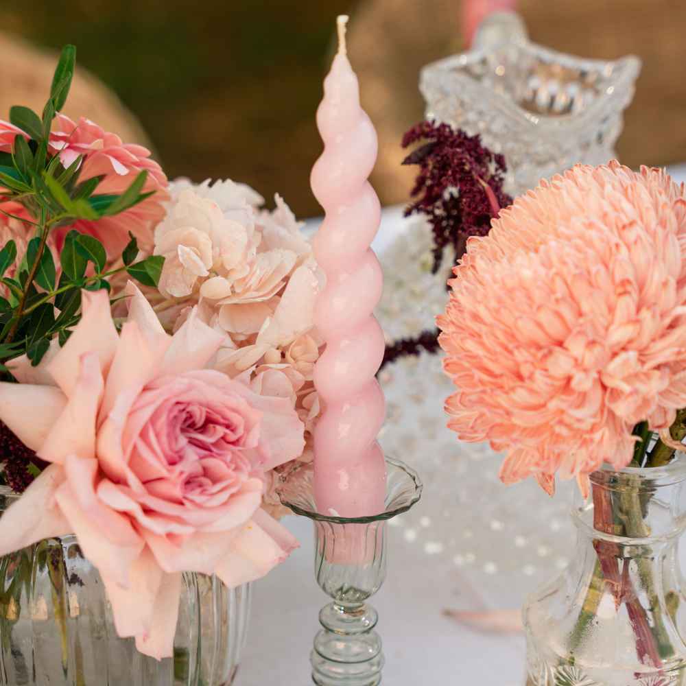 Decorative setup with pink candles and flowers on a blurred background