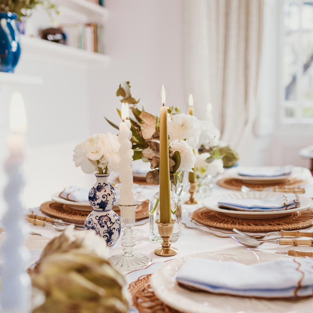 Elegant table setting with candles, flowers, and decorative plates in a bright room.