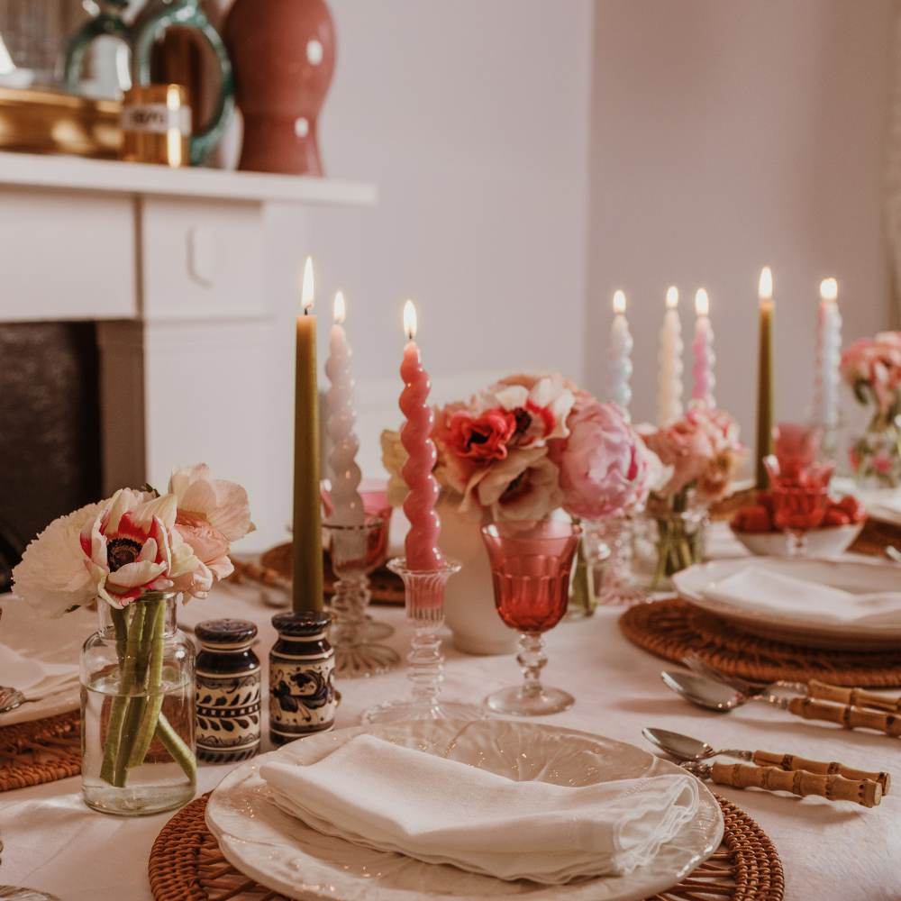 Elegant table setting with candles, flowers, and glassware in a cozy indoor setting.