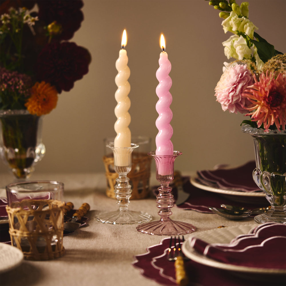 Decorative candles on a table with floral arrangements and tableware.