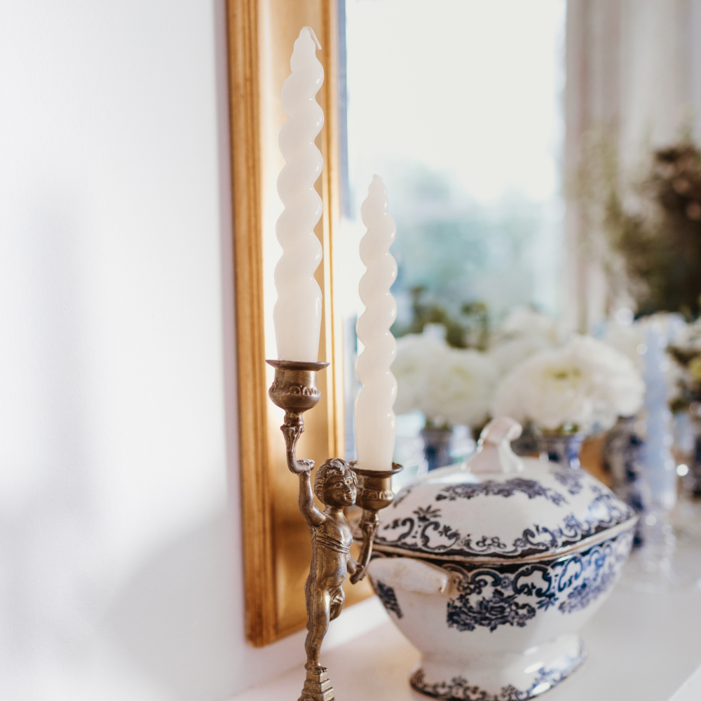 Decorative blue and white tureen with candles and a mirror in the background