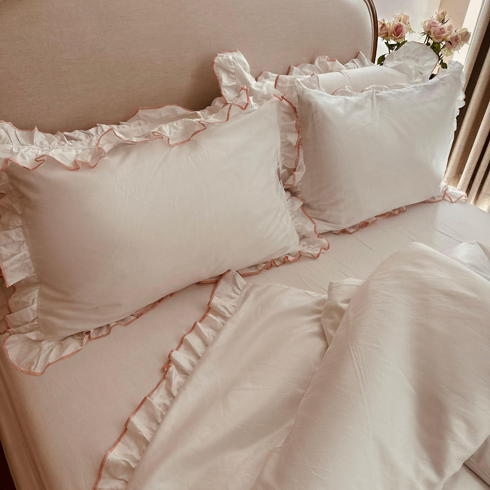Dusty Pink ruffled bedding set on a bed with a soft focus background