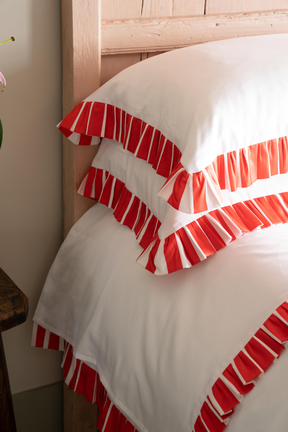 White pillow with red ruffle trim on a wooden bed frame.
