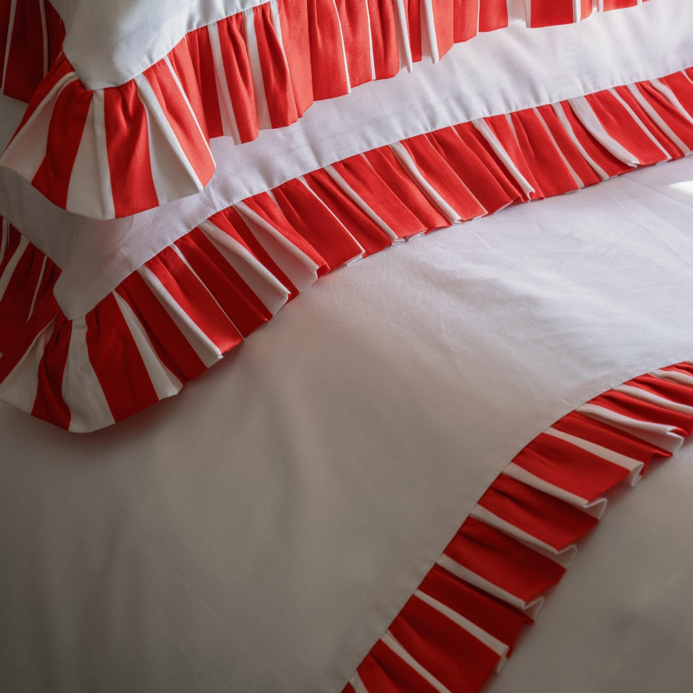 Red and white striped bedskirt on a bed with white bedding.