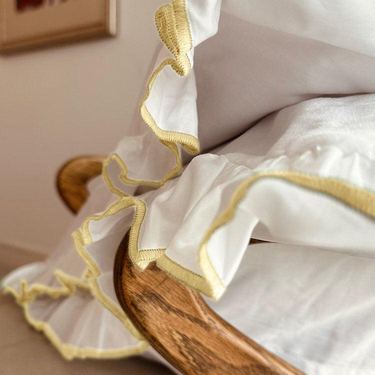 White pillowcase with yellow trim draped over a wooden surface