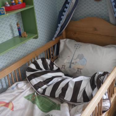 Children's room with a crib featuring a zebra-patterned blanket and colourful bedding.
